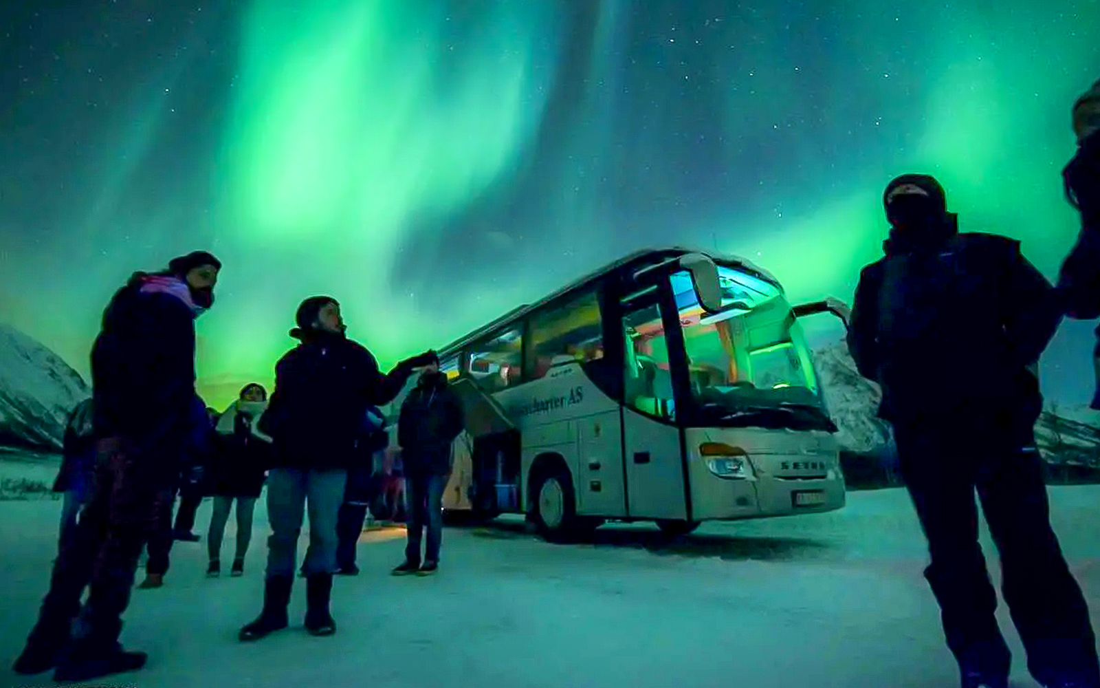Guests and bus under Northern Lights during chase tour.