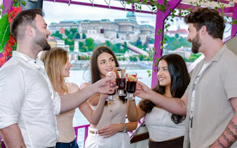 Group toasting with mulled wine on Danube River nighttime sightseeing cruise, Budapest.