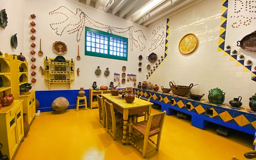 Frida Kahlo Museum kitchen with yellow furniture and traditional Mexican pottery.