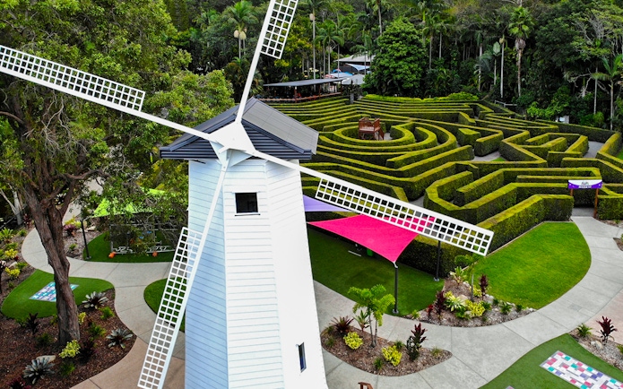 Windmill and hedge maze at Amaze World, surrounded by lush greenery.