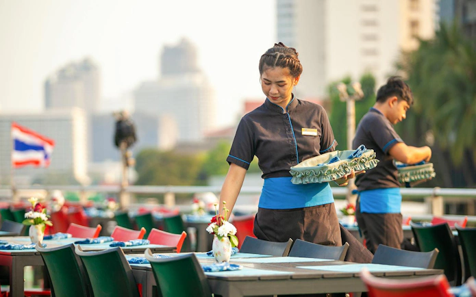 Waitstaff preparing tables on a Riverside Faraya Cruise in Bangkok.
