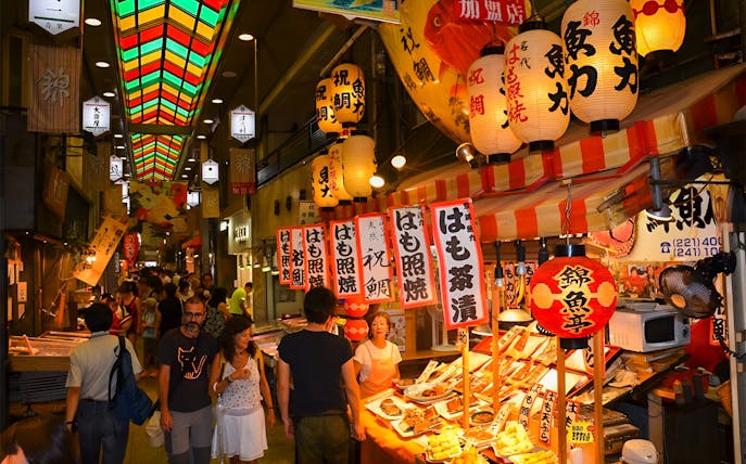 Nishiki Market in Kyoto with food stalls and colorful lanterns.