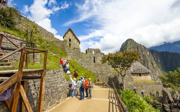 Tourists exploring stone structures at Machu Picchu, Peru.