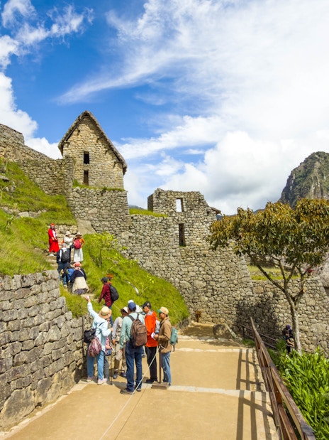 Tourists exploring stone structures at Machu Picchu, Peru.