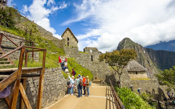 Tourists exploring stone structures at Machu Picchu, Peru.