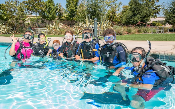 Group learning scuba diving basics in a pool at Palm Jumeirah, Dubai.