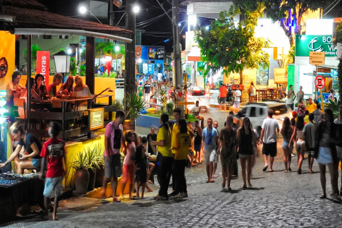 Crowded street in Pipa Village at night with people dining and exploring, Sao Paulo nightlife.