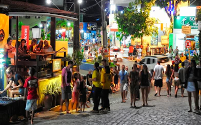 Crowded street in Pipa Village at night with people dining and exploring, Sao Paulo nightlife.