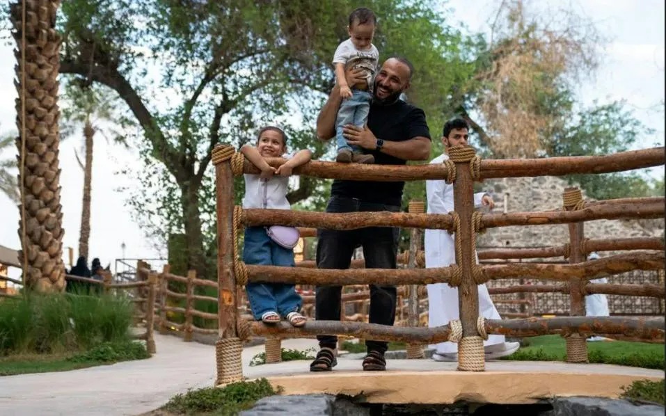 Family enjoying a scenic view at Bustan al-Mustazil, Medina, with rustic wooden railings.