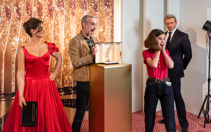 Wax figures at Grévin Paris with a girl reacting to a golden award display.