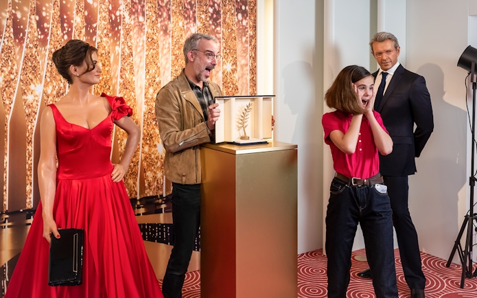 Wax figures at Grévin Paris with a girl reacting to a golden award display.