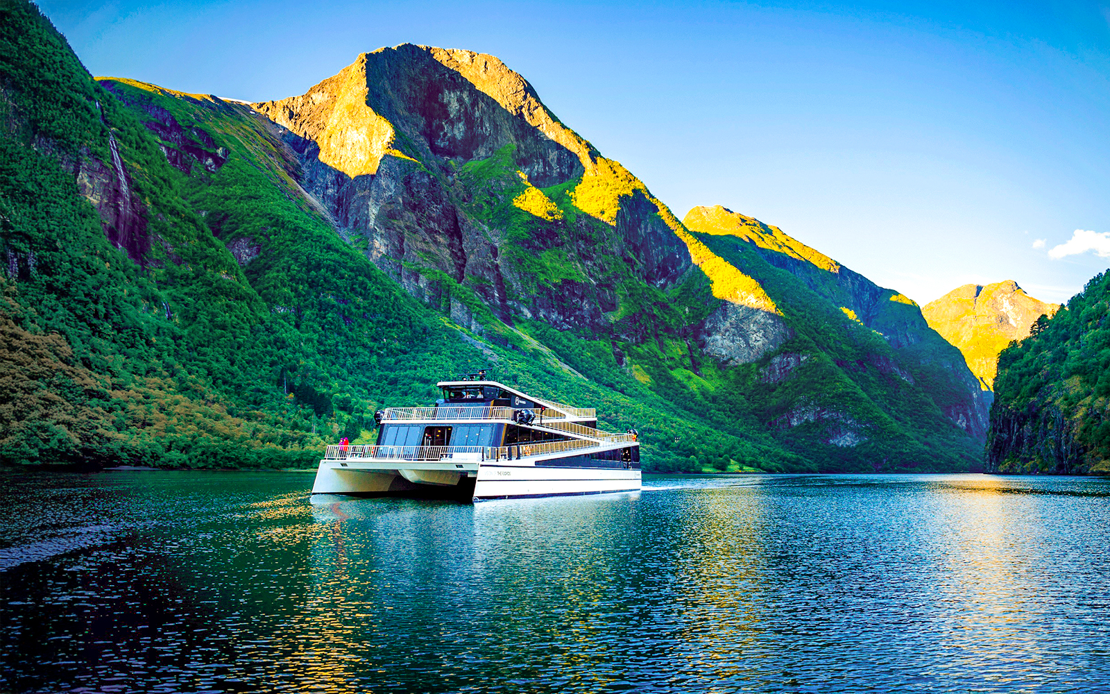 Cruise ship on Nærøyfjord surrounded by steep green mountains, Western Norway.