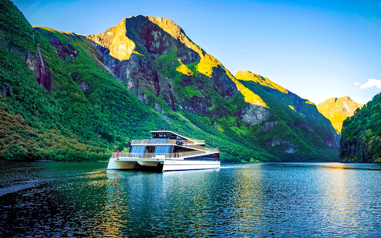 Cruise ship on Nærøyfjord surrounded by steep green mountains, Western Norway.