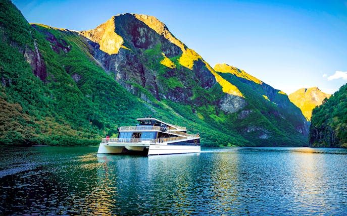 Cruise ship on Nærøyfjord surrounded by steep green mountains, Western Norway.