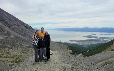 Tourists on Ushuaia Martial Glacier with panoramic view of mountains and sea.