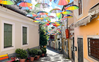 Cobbled street in Szentendre, Hungary, with colorful umbrellas hanging above.