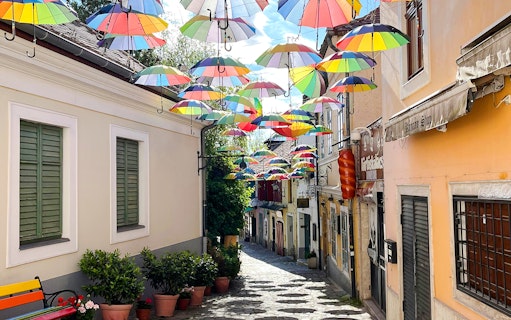Cobbled street in Szentendre, Hungary, with colorful umbrellas hanging above.