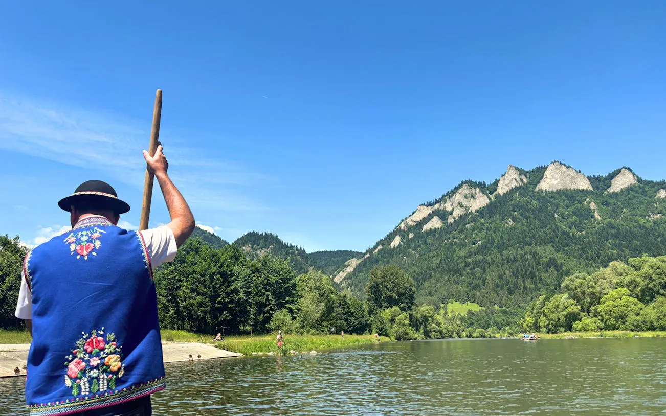 Raft guide on Dunajec River with Pieniny Mountains in background, Krakow day trip.