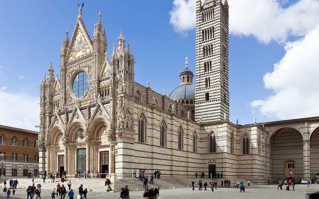 Siena Cathedral facade with visitors in Tuscany, Italy.