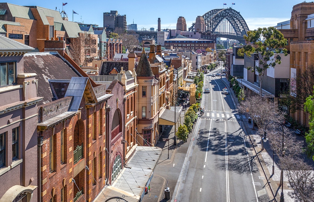Historic street view in The Rocks, Sydney, with the Sydney Harbour Bridge in the background.