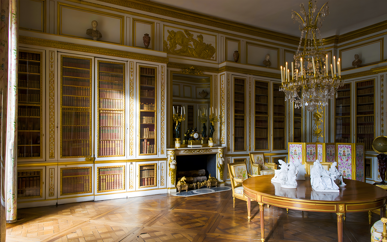 Louis XVI's Library in Versailles' King's Private Apartment with ornate bookshelves and chandelier.