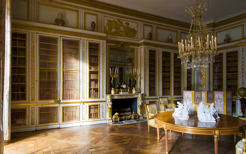 Louis XVI's Library in Versailles' King's Private Apartment with ornate bookshelves and chandelier.