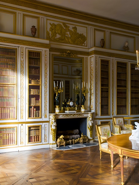 Louis XVI's Library in Versailles' King's Private Apartment with ornate bookshelves and chandelier.
