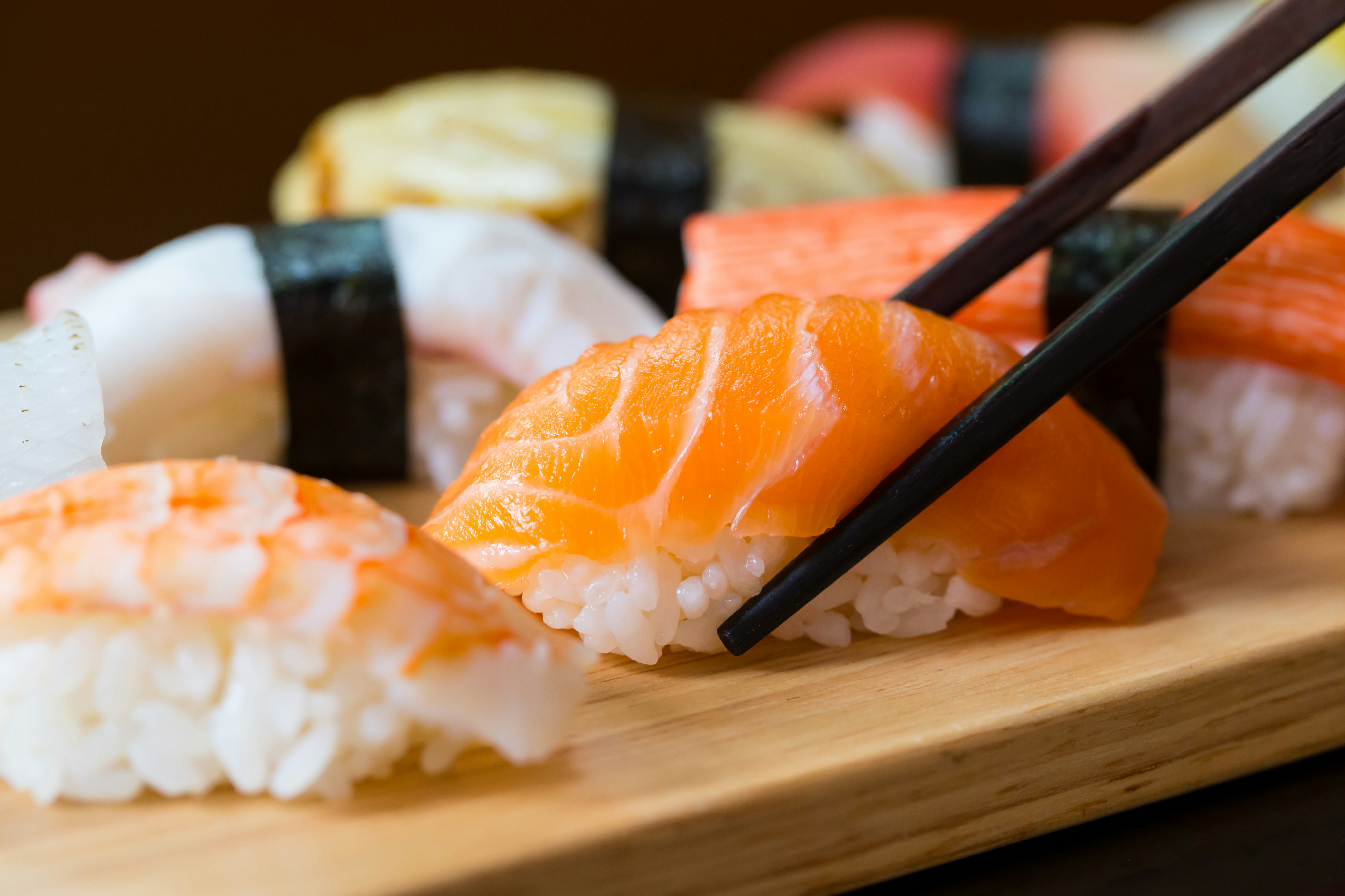 Assorted sushi set with salmon nigiri on wooden platter.