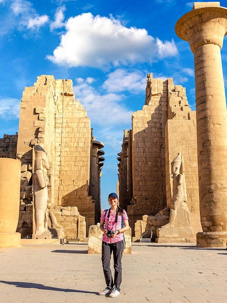Tourist exploring Luxor Temple with ancient columns and statues, Egypt.