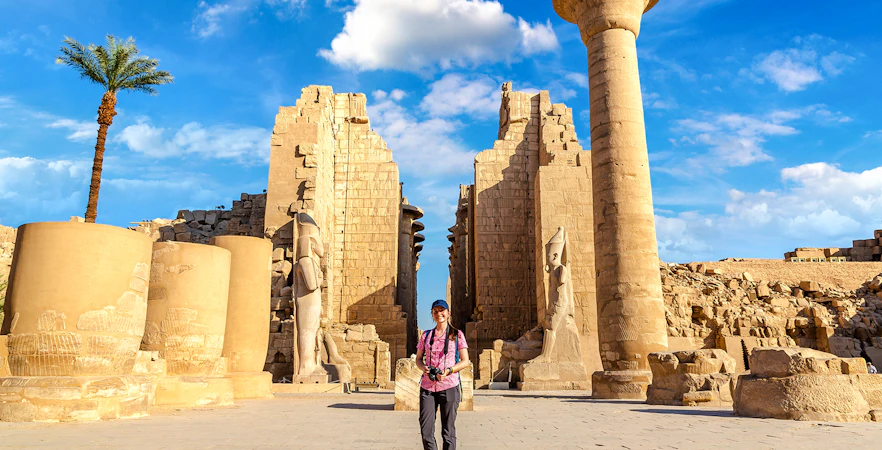 Tourist exploring Luxor Temple with ancient columns and statues, Egypt.
