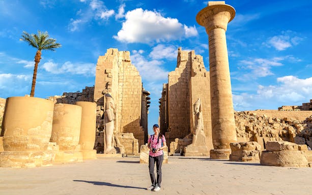 Tourist exploring Luxor Temple with ancient columns and statues, Egypt.