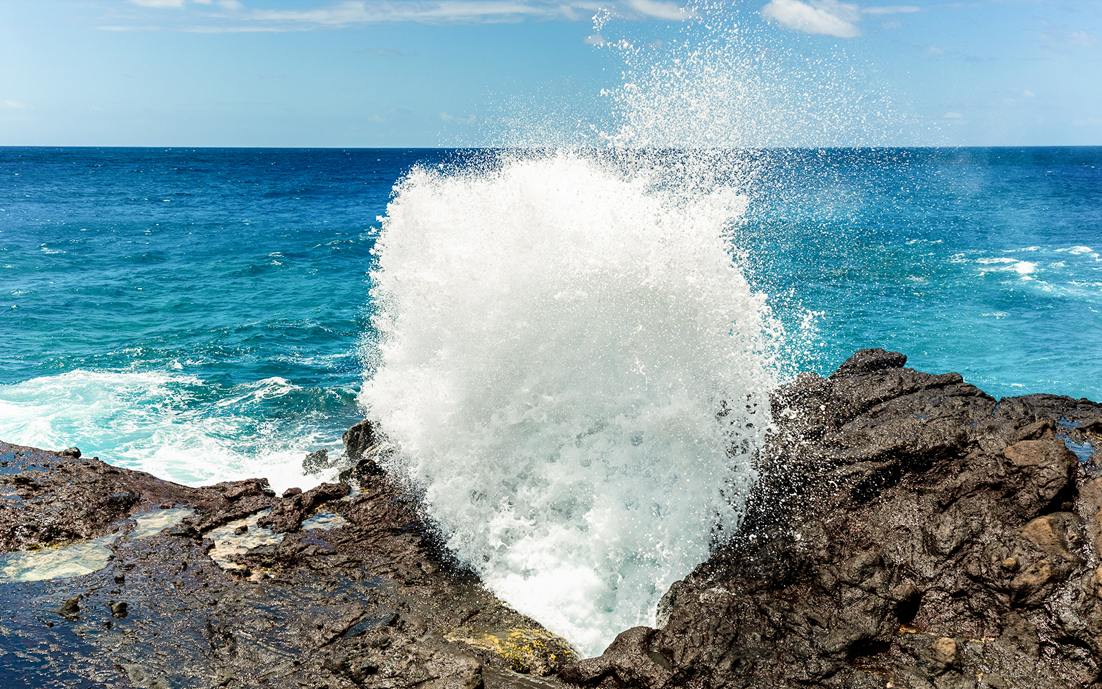 Halona Blowhole spouting water against rocky coastline, Oahu, Hawaii.