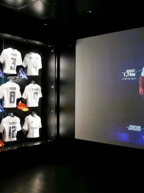 Football jerseys and player stats display at Santiago Bernabéu Stadium tour.