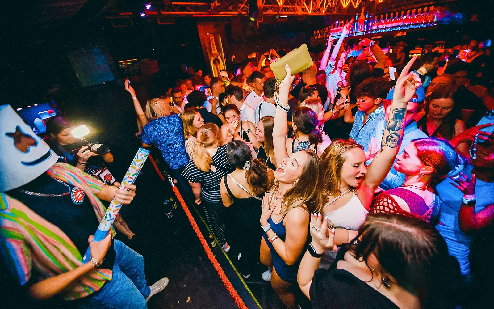 Partygoers dancing at a lively Prague boat party with vibrant lights.