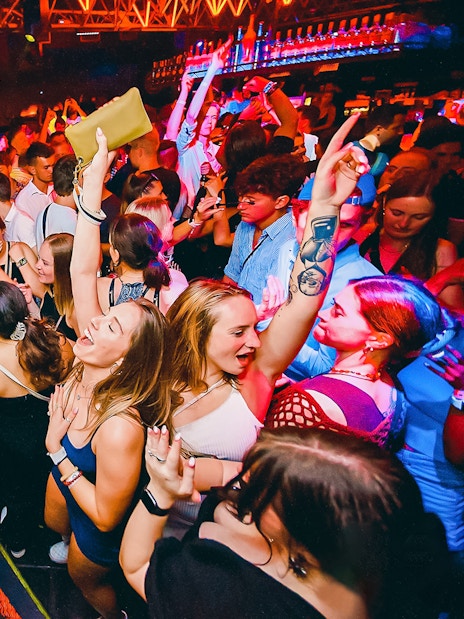 Partygoers dancing at a lively Prague boat party with vibrant lights.