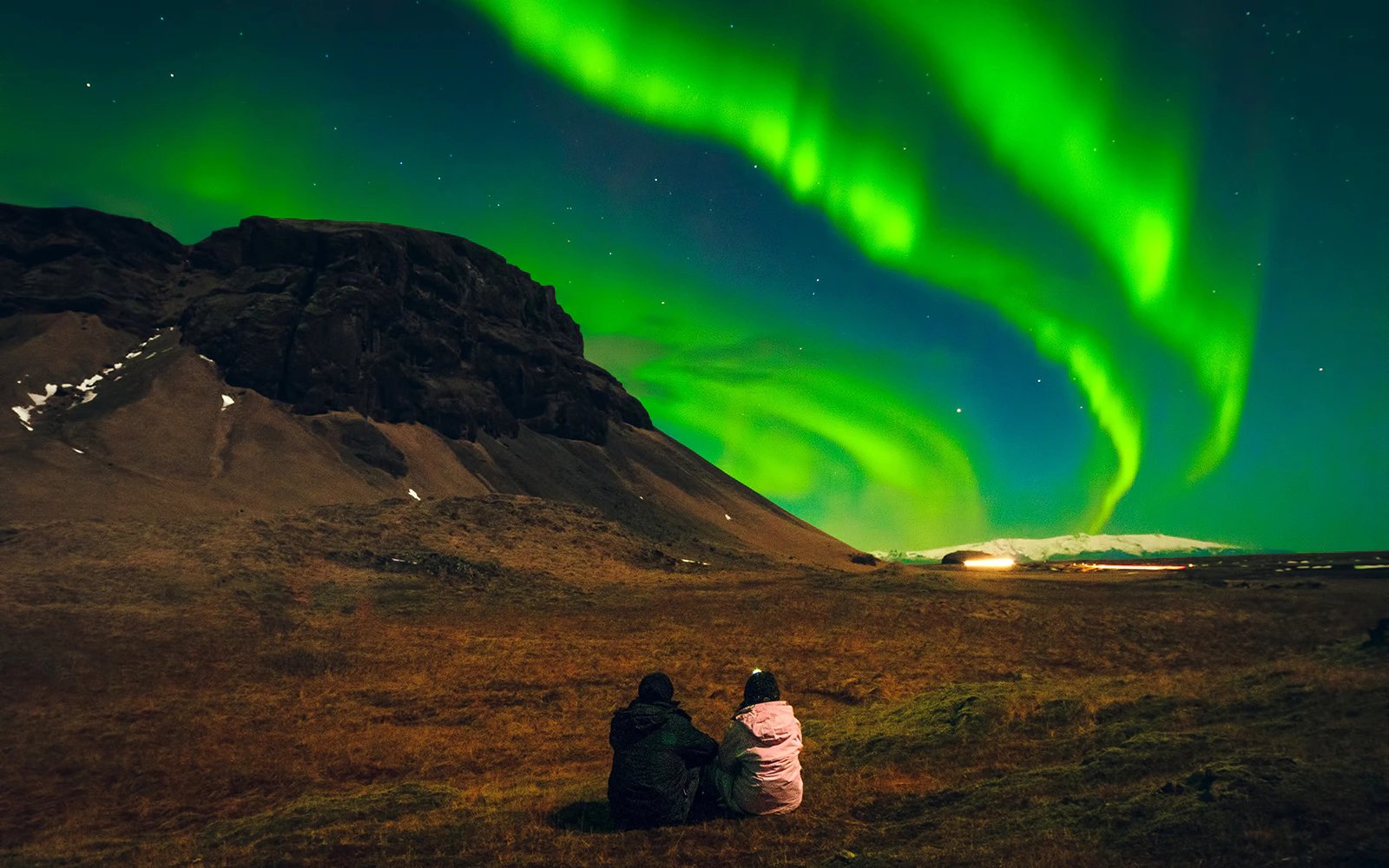 Two people watching the Northern Lights in Iceland.