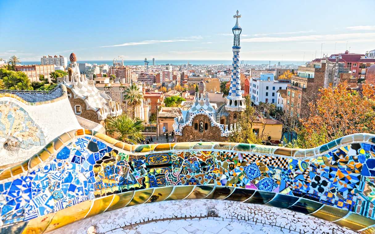 Panoramic view of Park Güell's colorful mosaic terrace overlooking Barcelona.