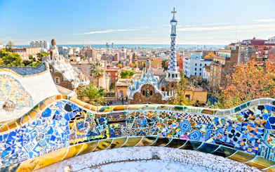 Panoramic view of Park Güell's colorful mosaic terrace overlooking Barcelona.