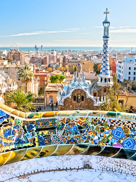Panoramic view of Park Güell's colorful mosaic terrace overlooking Barcelona.