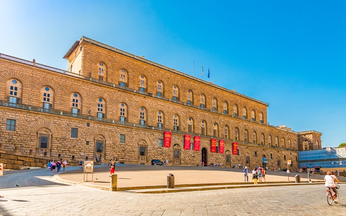 Palazzo Pitti facade in Florence with visitors and clear blue sky.