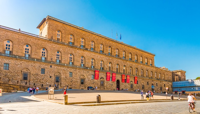 Palazzo Pitti facade in Florence with visitors and clear blue sky.