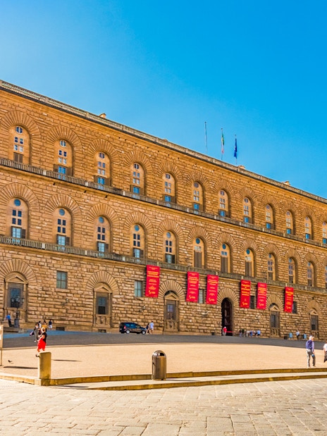 Palazzo Pitti facade in Florence with visitors and clear blue sky.