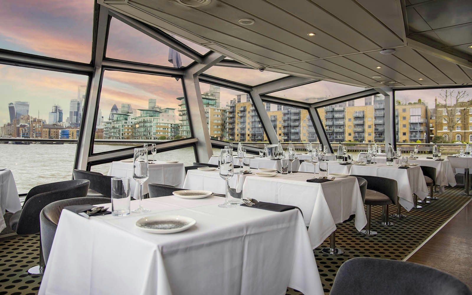 River Thames dinner cruise dining area with tables set for guests in London.