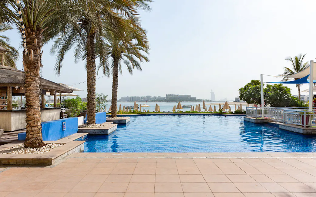 Piscine, palmiers et vue mer à Riva Beach Club Dubai