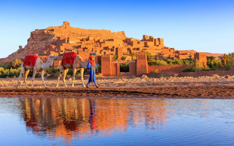 Person leading camels in front of Ait Benhaddou, Morocco.