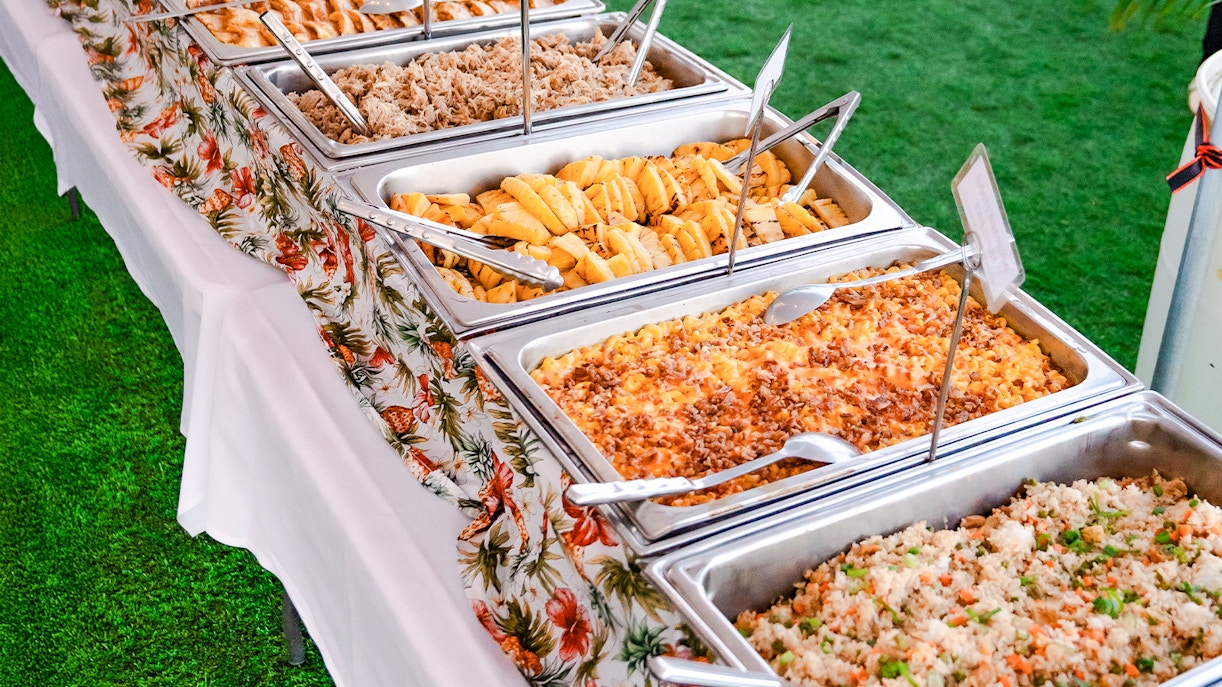 Buffet spread at Mauka Warriors Luau in Hawaii featuring various dishes.