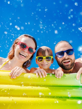 Family enjoying a sunny day at a waterpark with inflatable float.