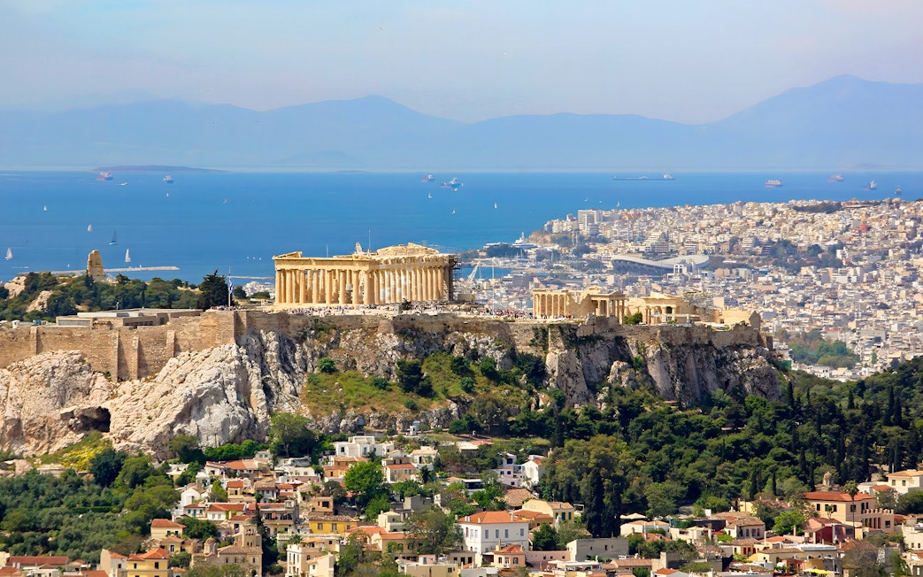 Acropolis on a hill overlooking Athens cityscape and sea.