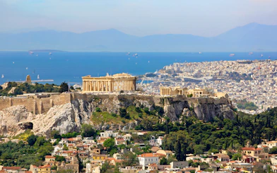 Acropolis on a hill overlooking Athens cityscape and sea.