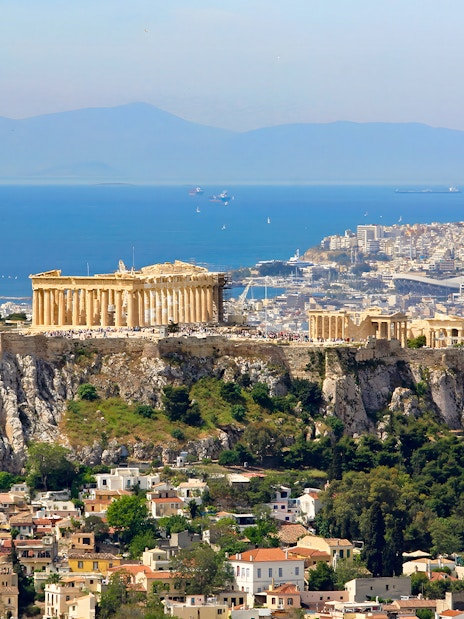 Acropolis on a hill overlooking Athens cityscape and sea.